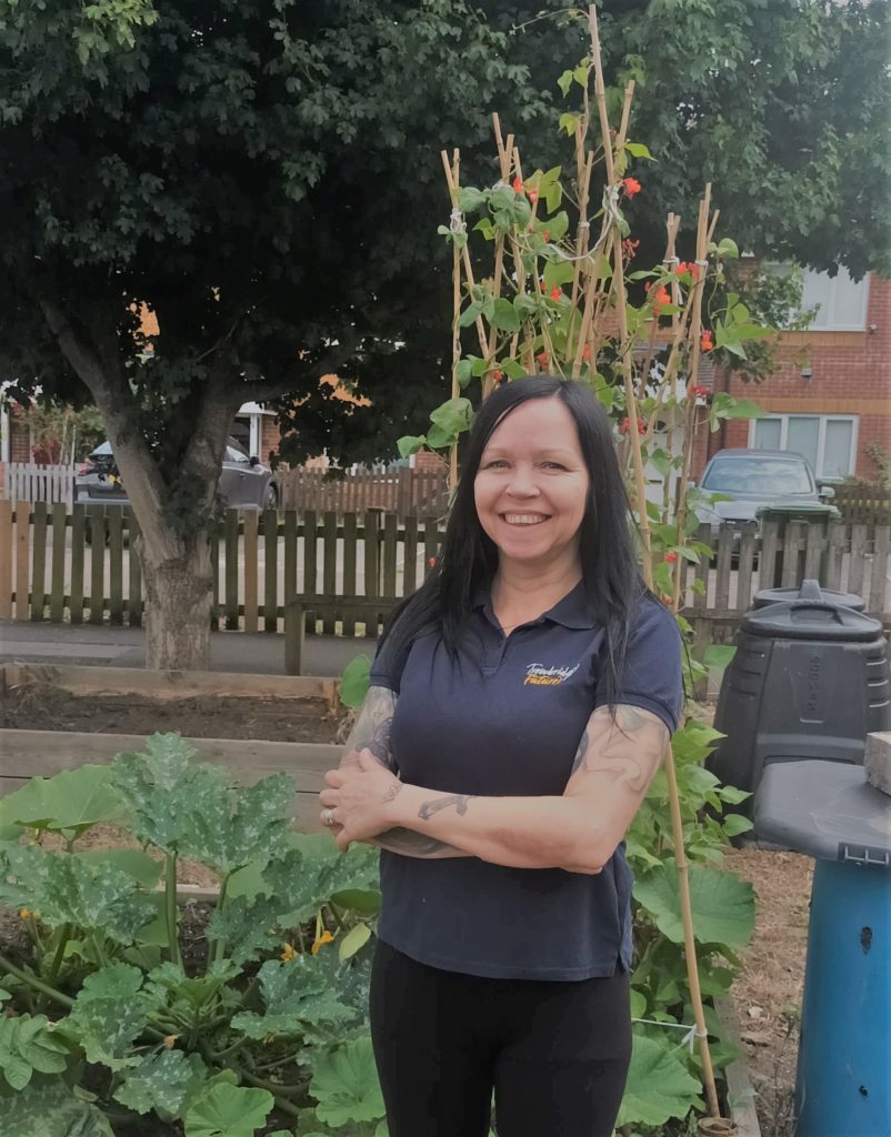 Zoe, community manager at Trowbridge Future standing in front of growing vegetables at community garden