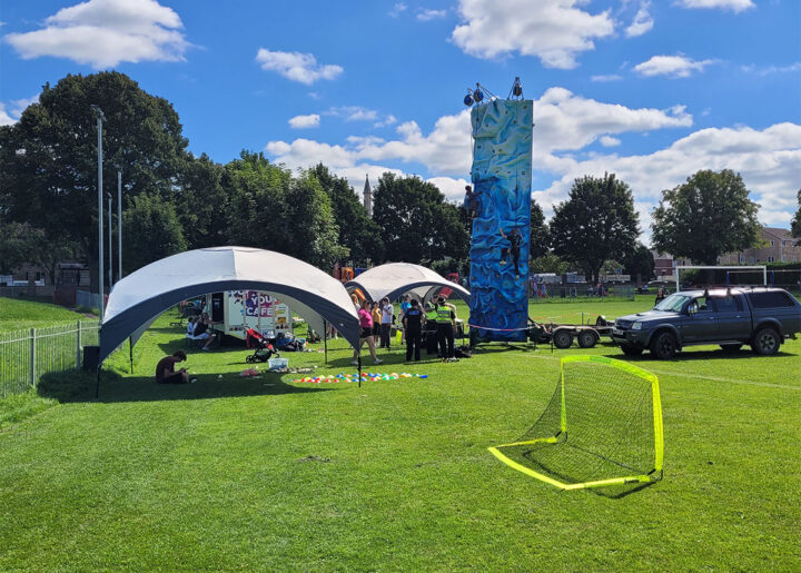 Picture of a field in Trowbridge with tent, climbing wall football net and pop up cafe event taking place