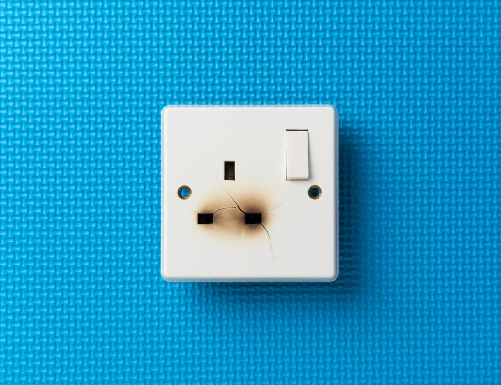 Burnt plug socket against a blue backdrop