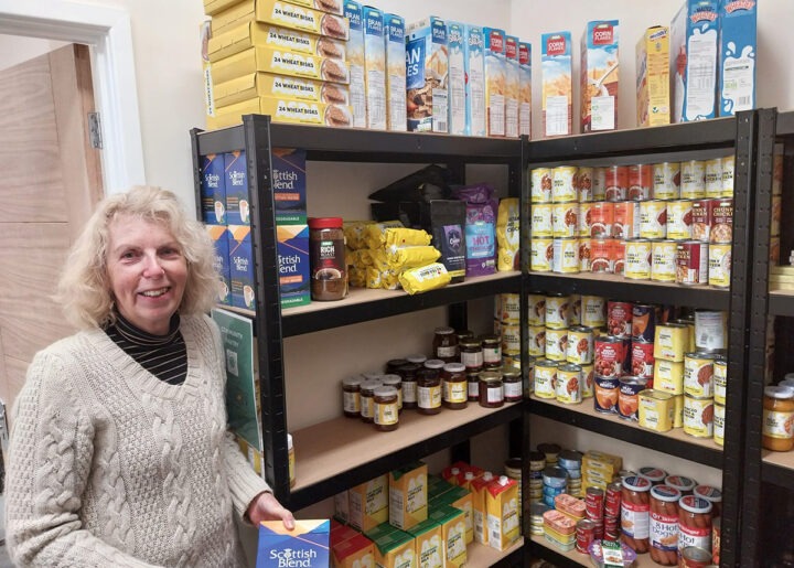 Volunteer standing next to food donations in new storeroom at Old Sarum and Longhedge community pantry