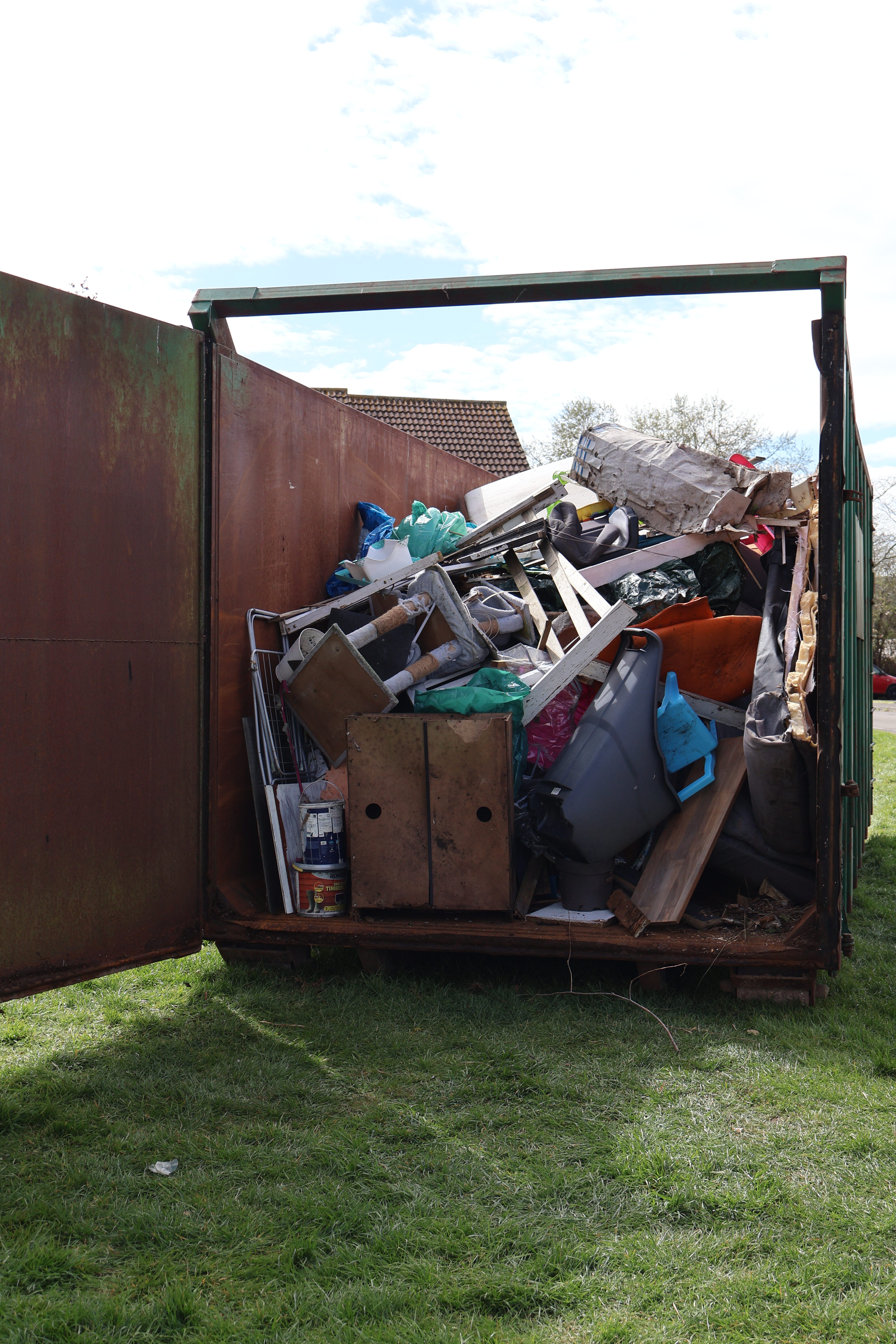 A large skip filled with items collected from an estate clearance.