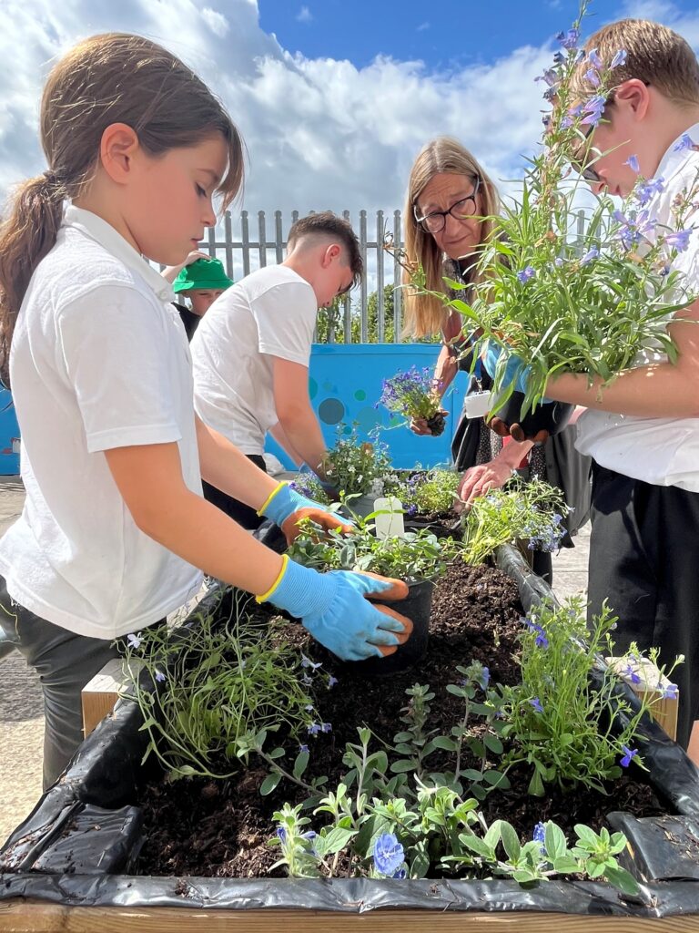 Children with TEAM10 help with planting