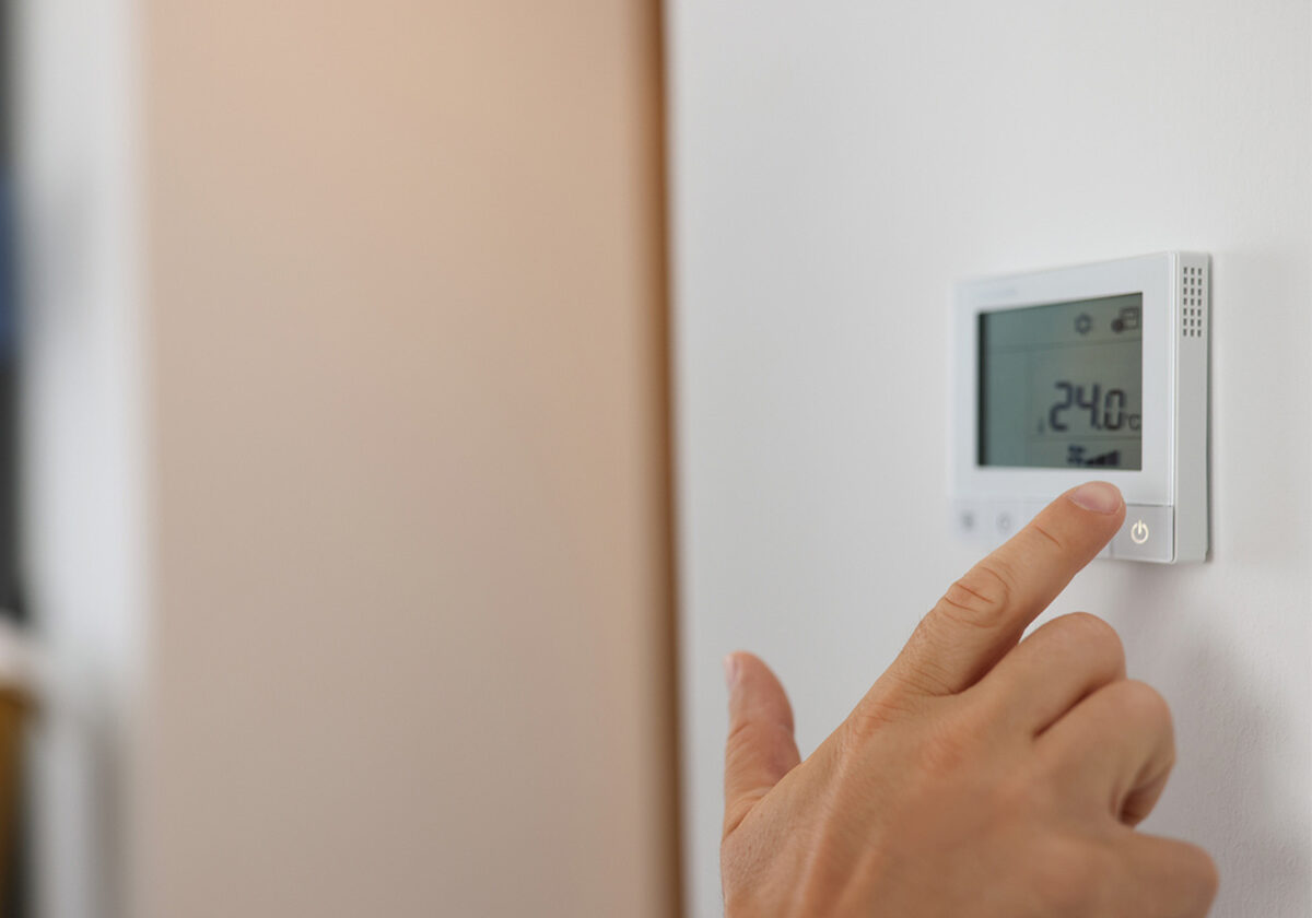 Close up of someone adjusting temperature control for their air source heat pump heating system